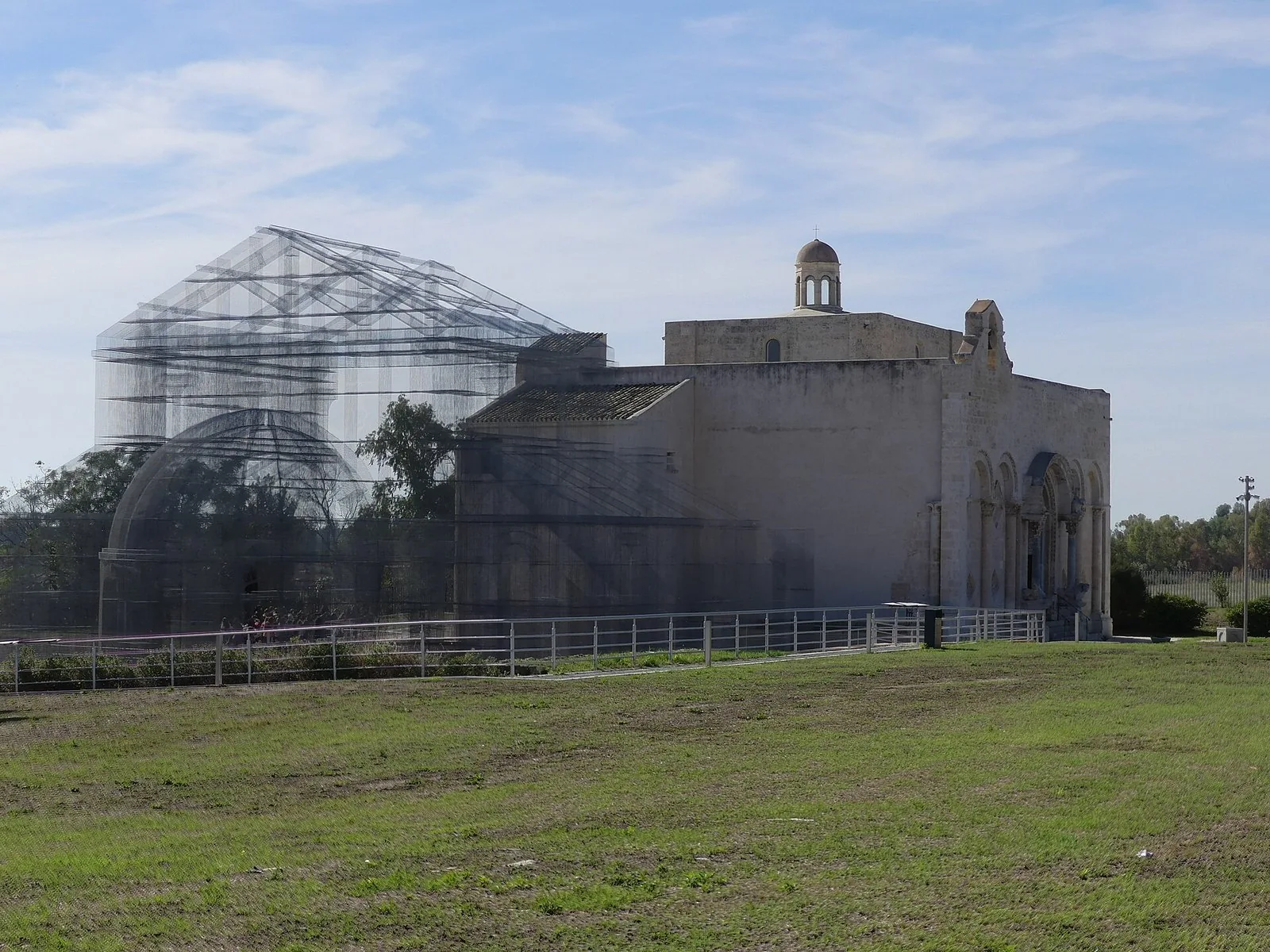La basilica romanica di Santa Maria Maggiore di Siponto accanto all'installazione in rete metallica che ricostruisce la chiesa paleocristiana.